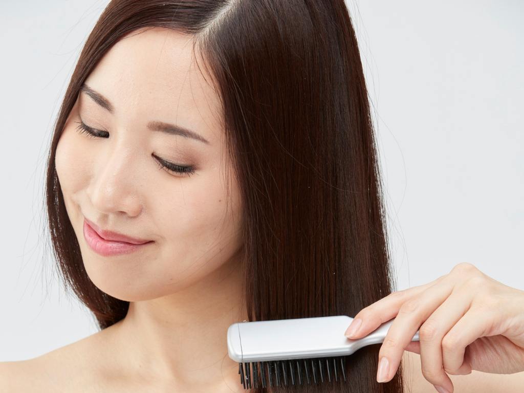 Mulher escovando cabelo solto com risca no meio