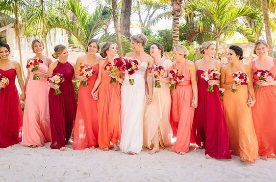 Madrinhas com vestidos que vão do bege ao vermelho. O efeito e contraste com o vestido branco da noiva é incrível!