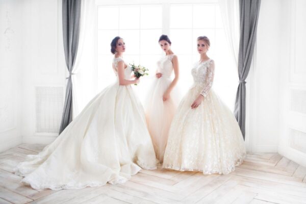 três mulheres vestindo vestido de noiva estilo princesa