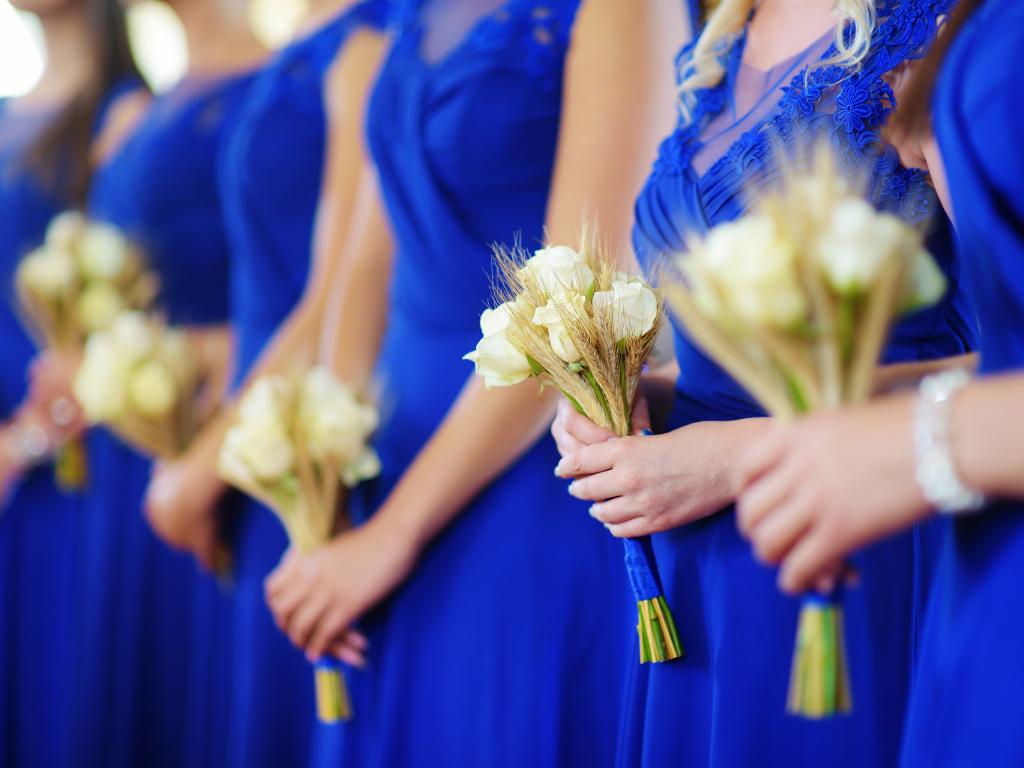 madrinhas de casamento com vestidos na cor azul e buquês nas mãos