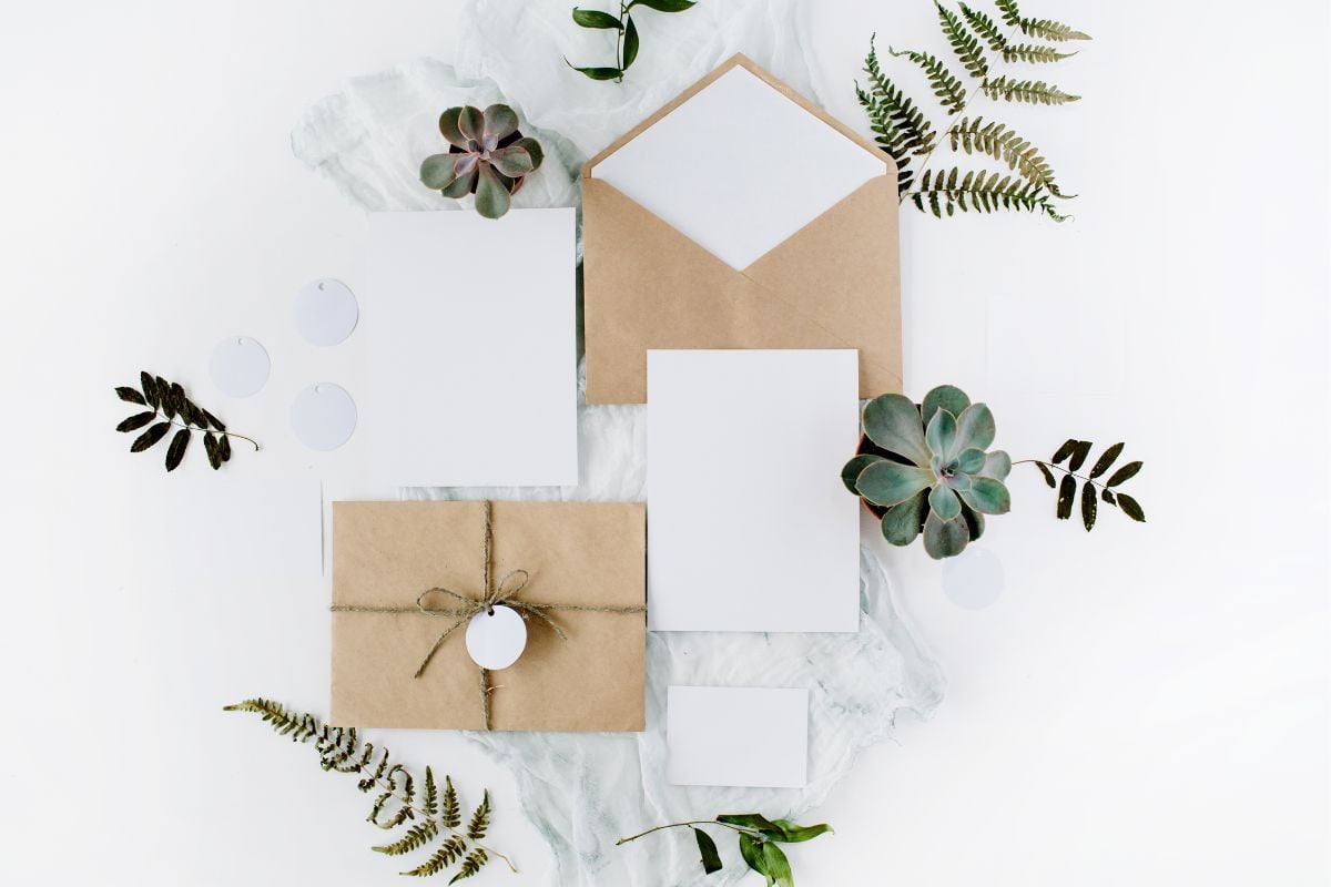 convite de casamento em fundo branco com plantas verdes.