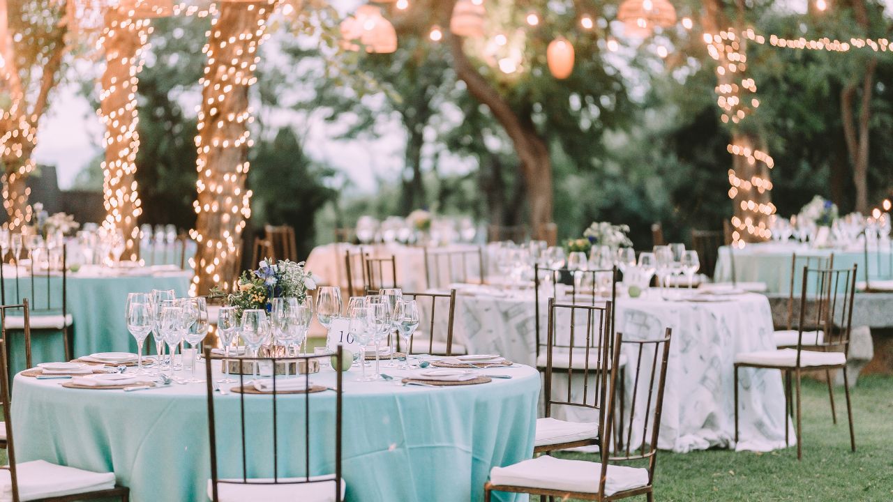 espaço para casamento com cadeiras e mesas com toalhas e iluminação