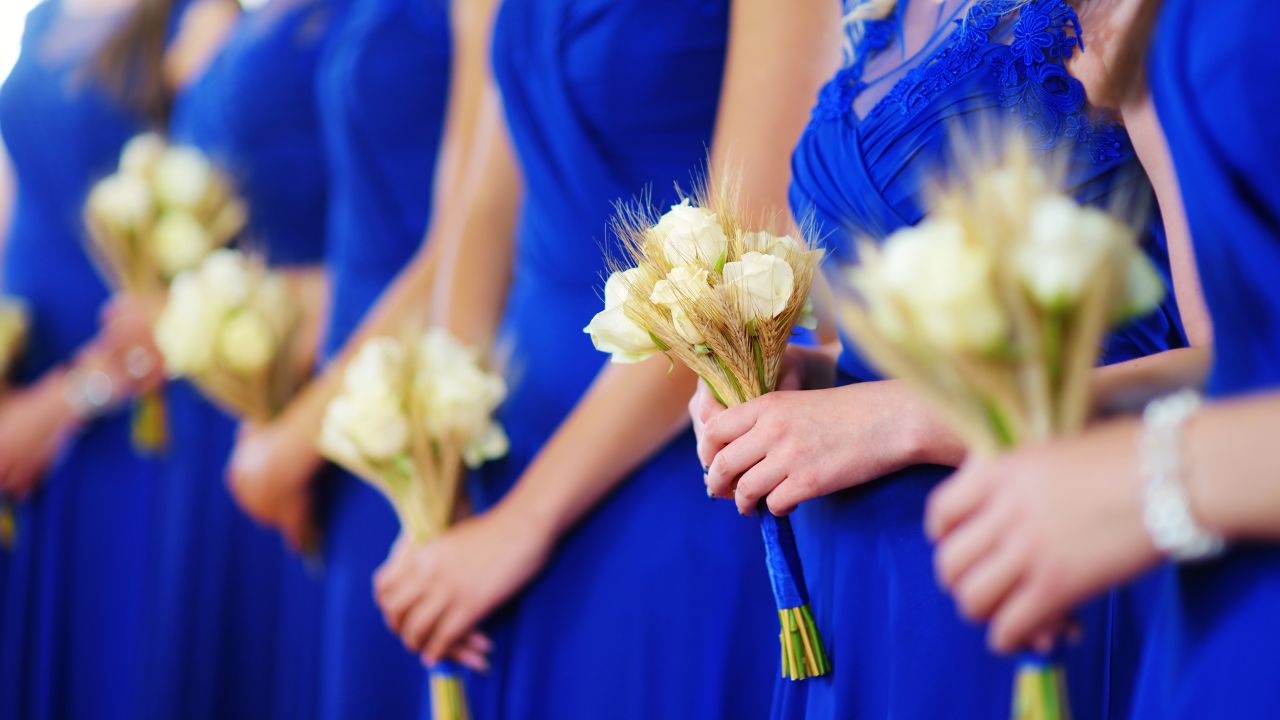 mulheres de vestidos de madrinha azul segurando pequenos buquês