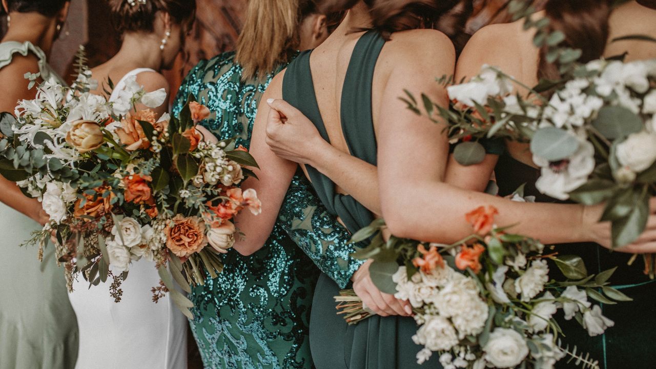 mulheres de costas com vestidos verde de madrinha de casamento e uma noiva 