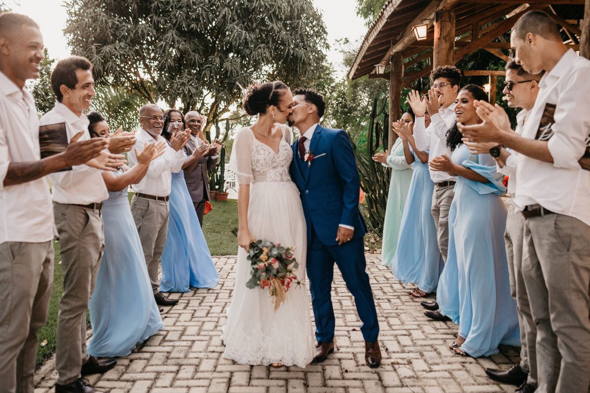 casal se beijando em casamento e convidados ao redor