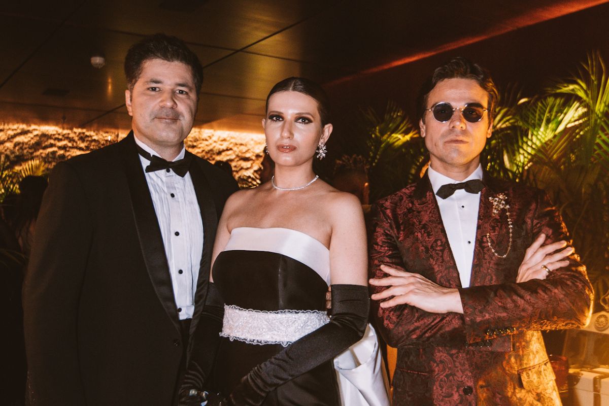 dois homens e uma mulher com roupas de gala em um evento