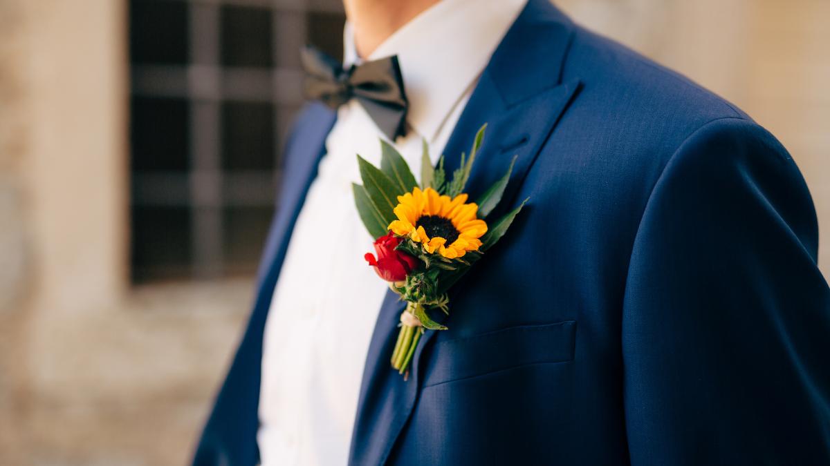 Homem de paletó com flores na lapela.