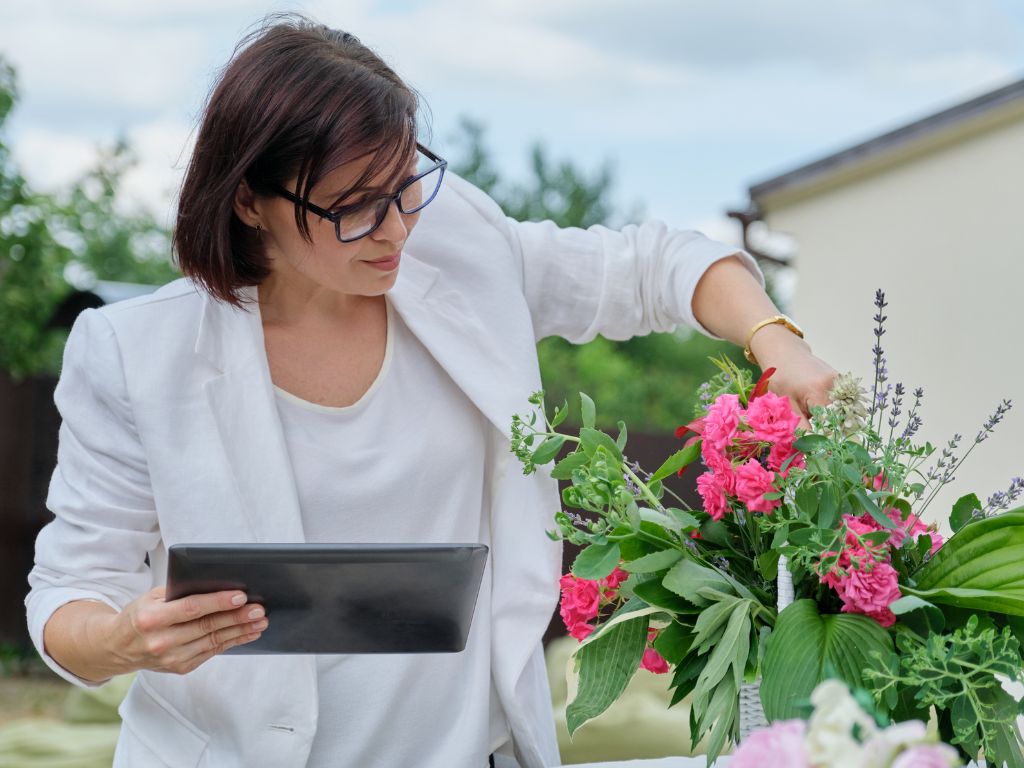 mulher de cabelo curto com blazer branco arrumando flores