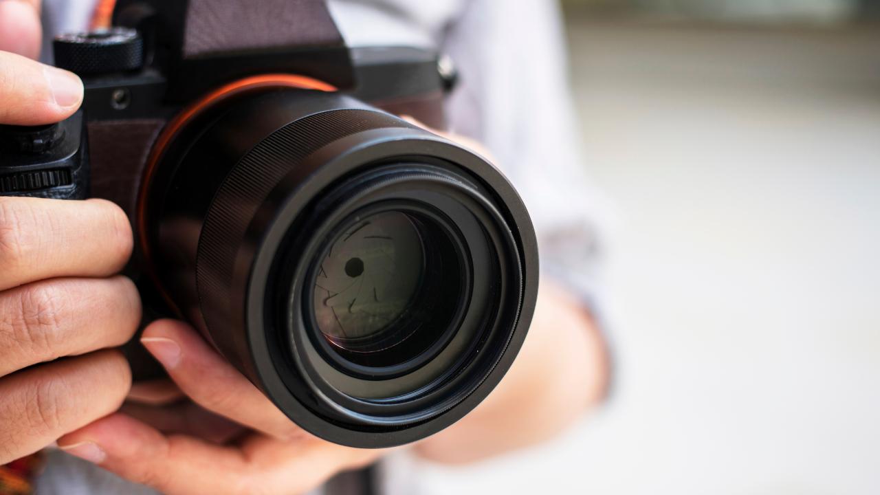 Mãos segurando uma máquina fotográfica preta.