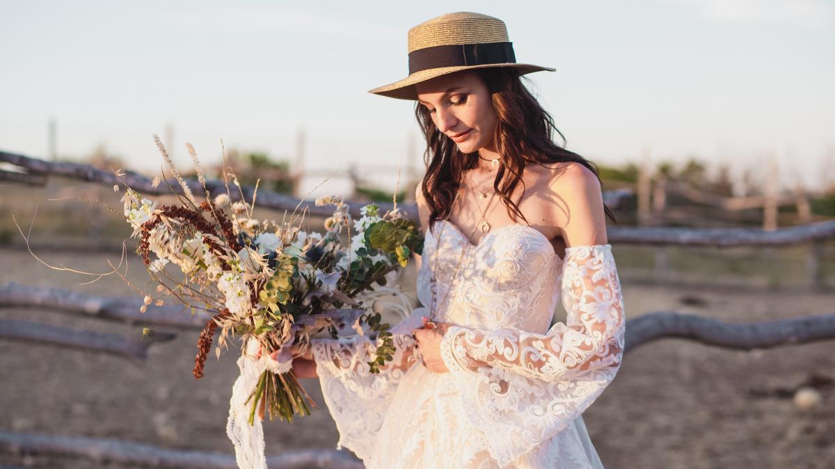 Noiva usando chapéu, um acessório comum no casamento boho chic, e segurando um buquê.