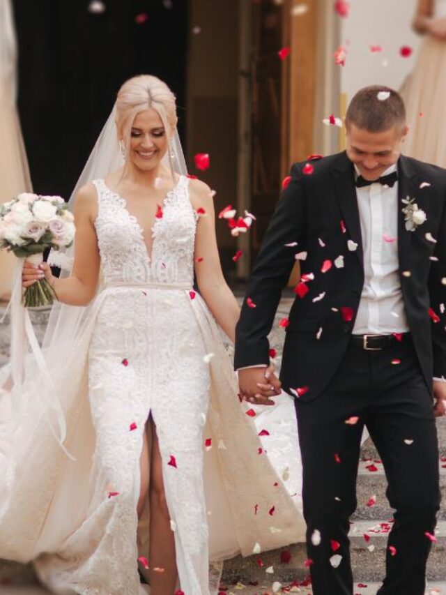 Casal saindo da igreja sendo recepcionado por pétalas de flores.