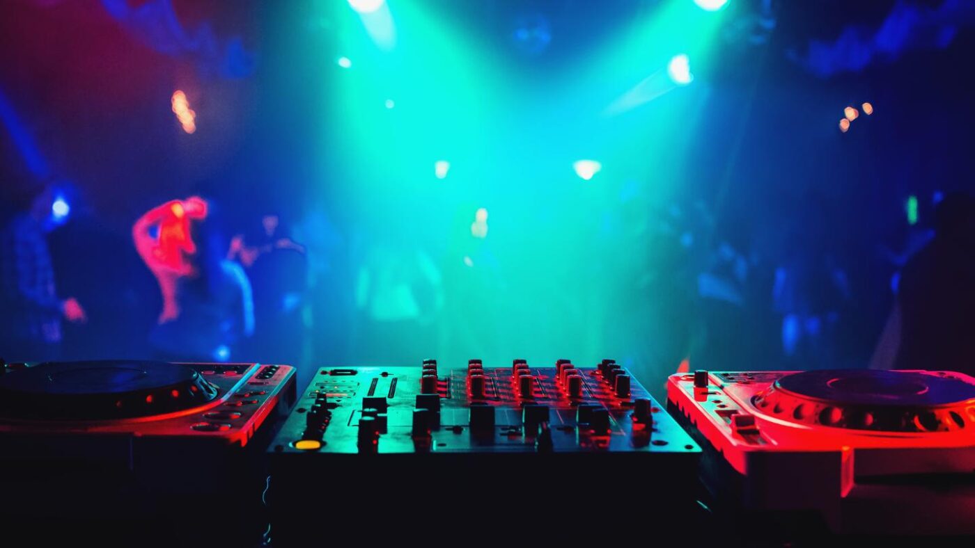 Mesa de DJ com luzes coloridas na pista de dança.