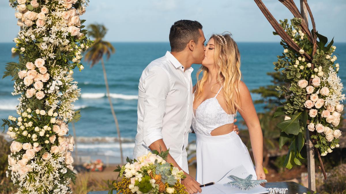 Flores para compor altar de casamento na praia e casal se beijando 