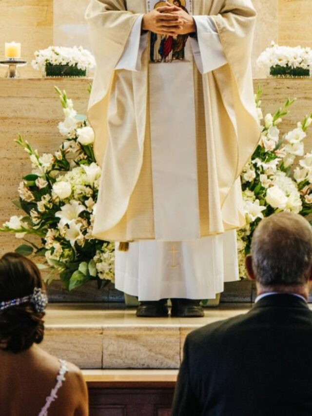 Noivos e padre em altar de igreja decorado.