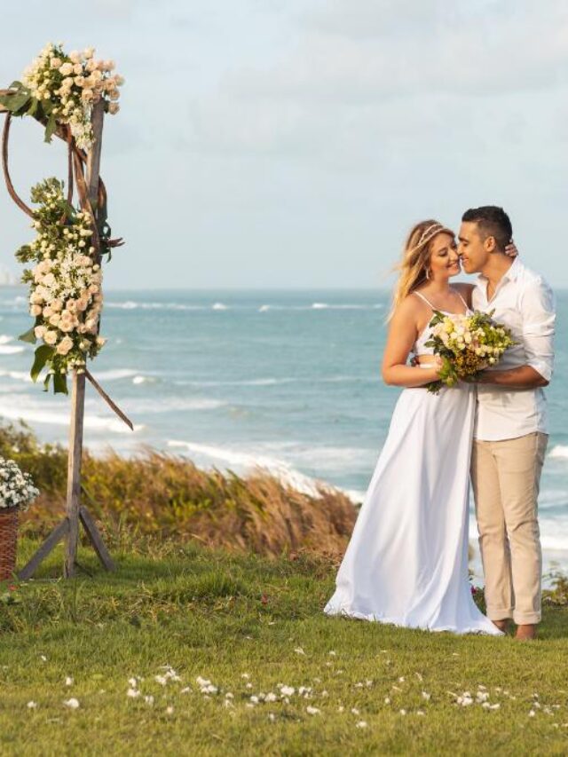 Casal ao lado de decoração para casamento na praia.