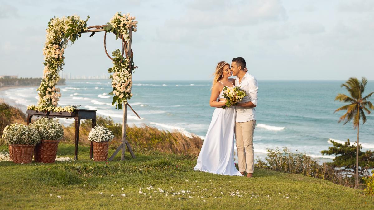 Casal ao lado de decoração para casamento na praia.