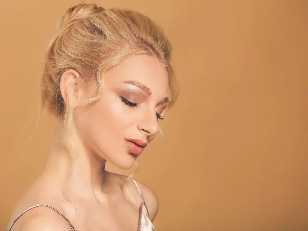 mulher loira com penteado de coque alto bagunçado