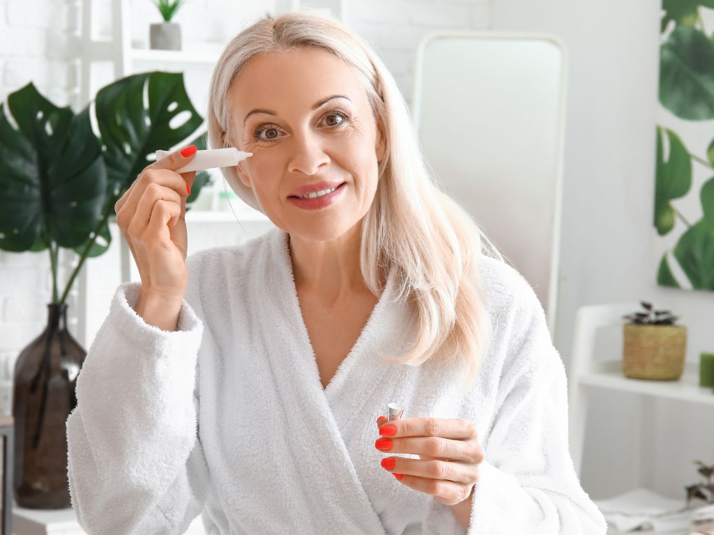 mulher aplicando creme na região dos olhos