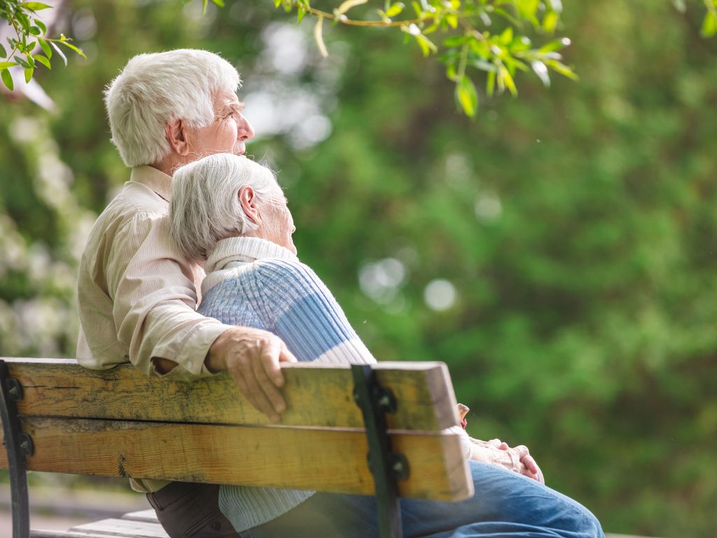 casal de idosos sentado em um banco de praça