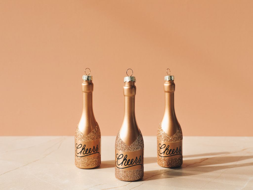 três mini garrafas de champanhe em um fundo pêssego
