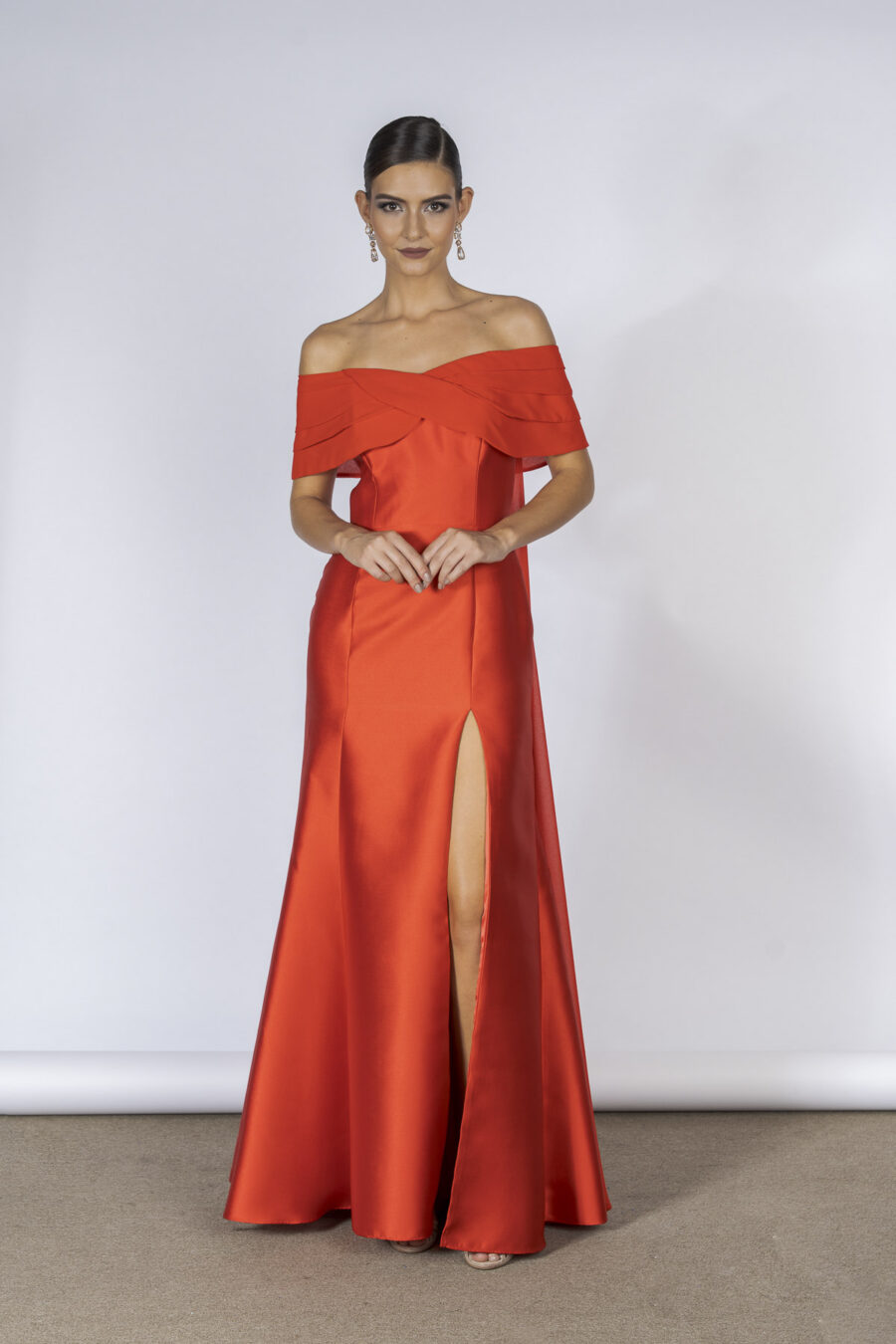 Vestido de festa longo com decote ombro a ombro e elegante semi sobrecapa, esse modelo em tecido de alfaiataria na cor vermelho é a aposta certa para você brilhar nos bailes e elegantes casamentos.