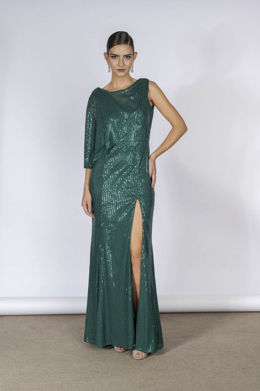 Vestido de festa longo em paetê verde, com modelagem moderna e elegante, esse modelo de vestido com fenda tem detalhes de sobreposição de tecidos que trazem elegância ao modelo, perfeito para mães dos noivos jovens usarem em casamentos.