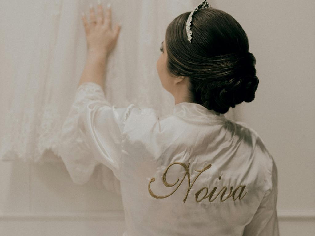Noiva olhando para seu vestido enquanto usa um robe de noiva