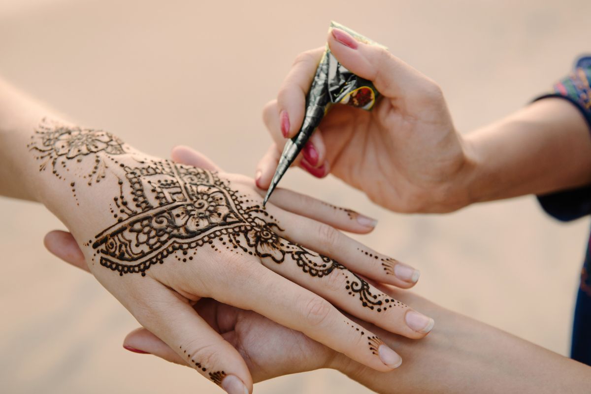 mão de uma mulher sendo aplicada hena durante um casamento muçulmano