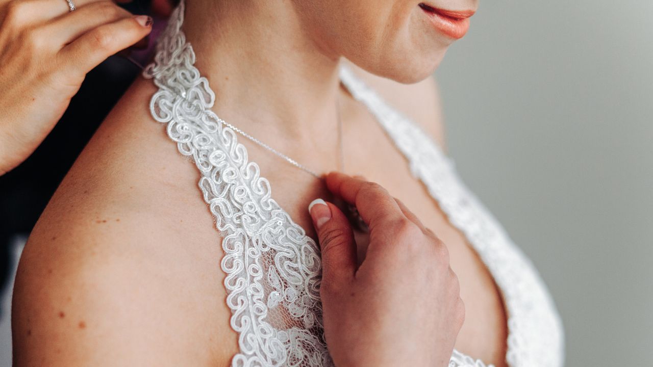 noiva com vestido bordado branco segurando colar no colo