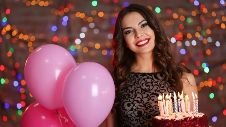 jovem em festa de 16 anos sorrindo com bolo em uma mão e balões rosa do lado