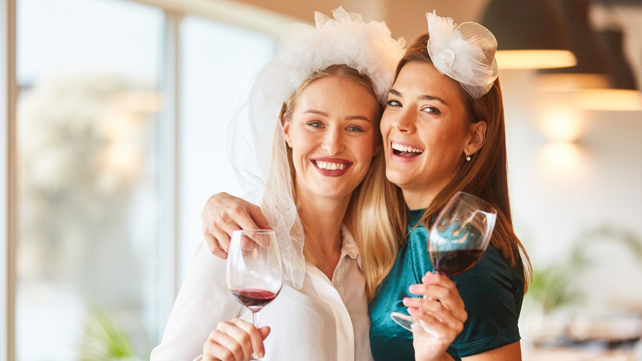 noiva e irmã com taças de vinho na mãe sorrindo