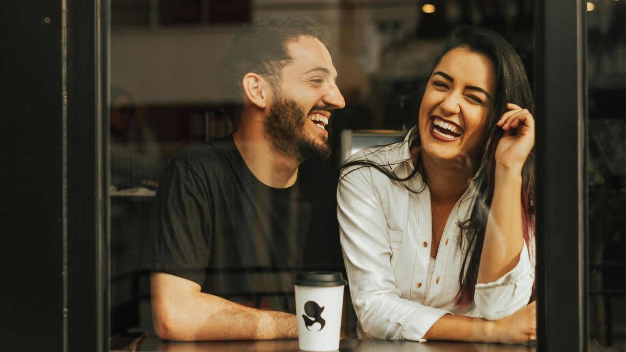 casal rindo em uma cafeteria durante ensaio de casal