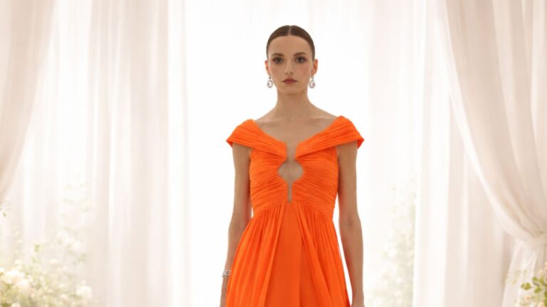 mulher com vestido de festa laranja arthur caliman em um ambiente de casamento com cortinas e flores