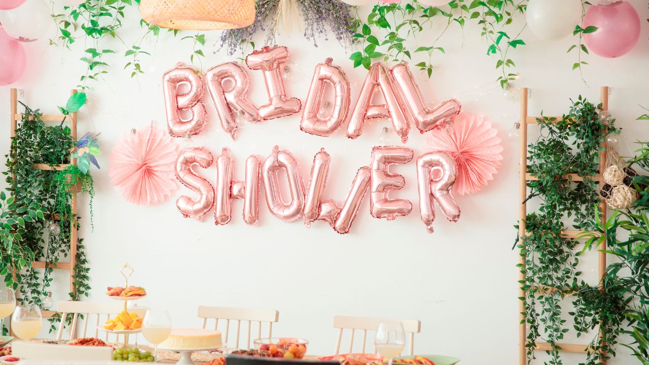 painel de bexigas rosa escrita bridal shower e plantas verdes em uma decoração de chá de lingerie