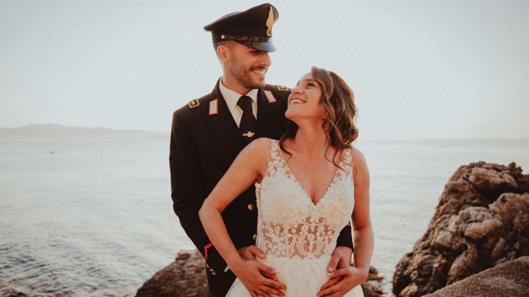 noiva na frente e noivo atrás sorrindo em um casamento militar