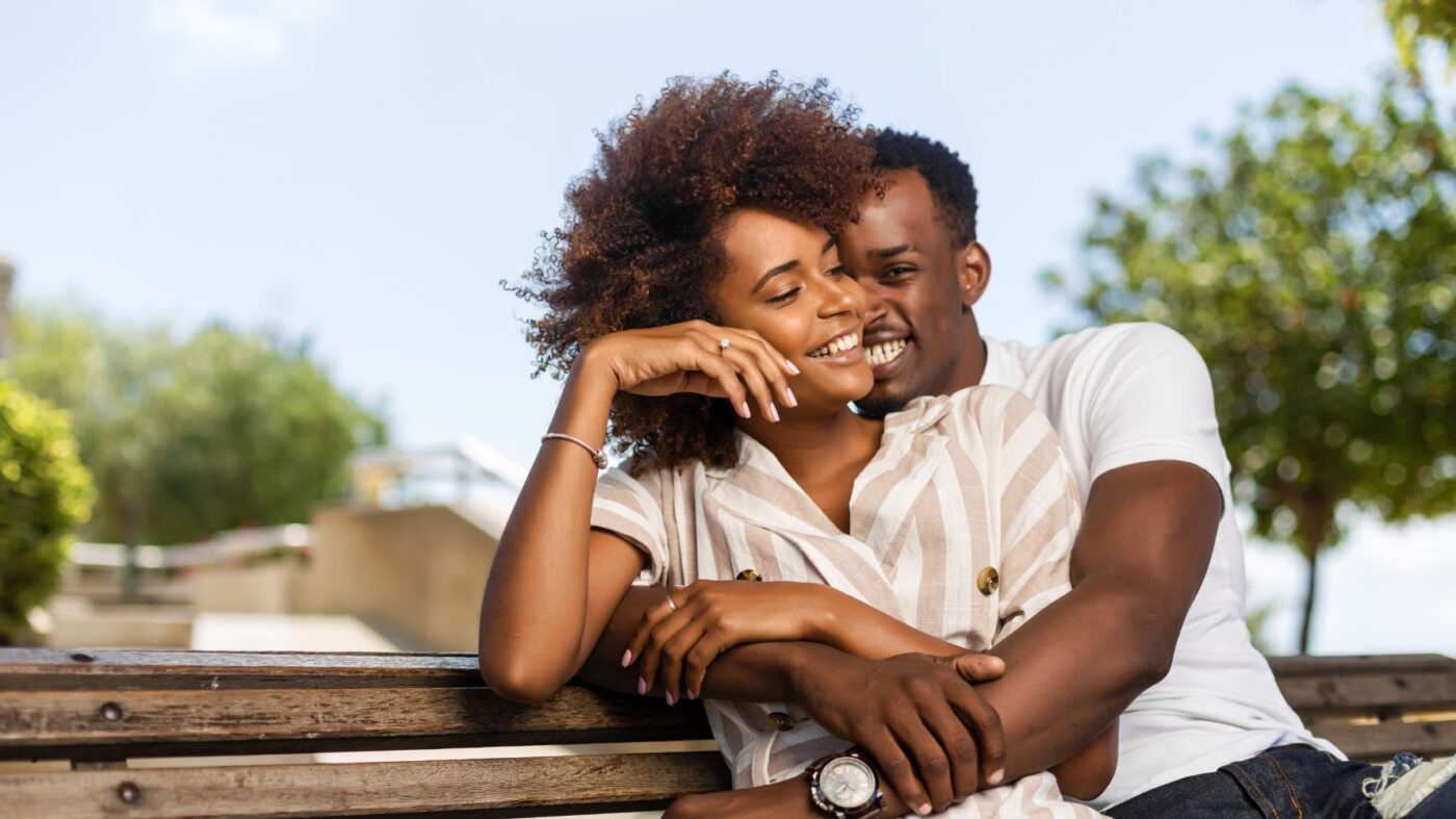 casal feliz sentado em banco sorrindo